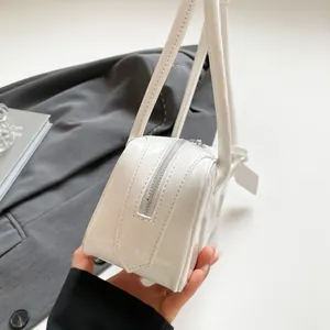 Close-up of white patent leather shoulder bag with silver metal zipper and dual straps