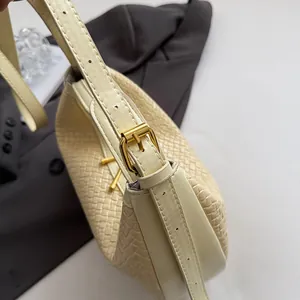 Close-up of beige woven texture and leather strap with gold buckle on crescent bag