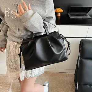 Detail of black pleated cloud bag with side drawstrings shown in a lifestyle scene