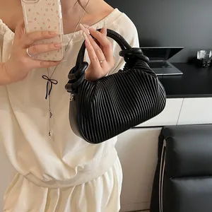 Détail d'un sac à main noir à texture plissée avec poignée nouée et boucles latérales