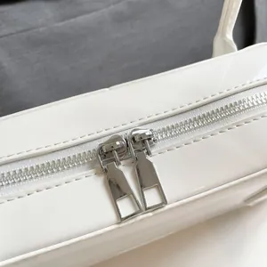 Macro shot of silver metal dual zipper closure on a white glossy leather handbag