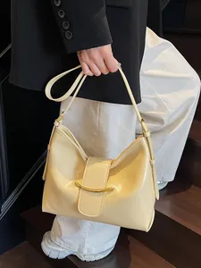 Minimalist beige leather bucket bag with gold metal buckle shown in a lifestyle street shot