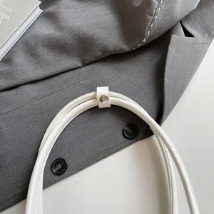 Detailed close-up of white leather handbag handles with silver metal snap button fastener