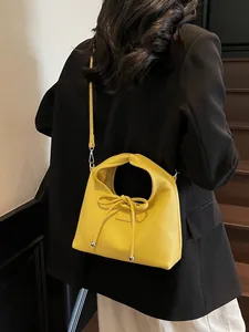 Minimalist bright yellow lychee leather handbag with a twisted handle and bow detail