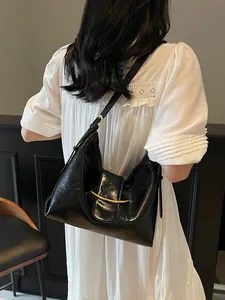 Minimalist black glossy leather bucket bag with crescent gold buckle on a shoulder strap