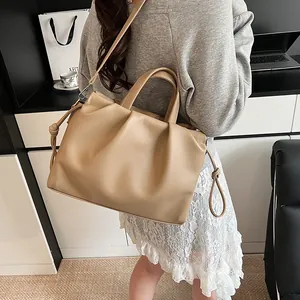Detailed close-up of a large ruched beige leather tote bag with stylish knot accents