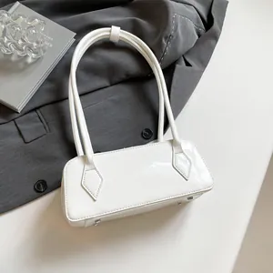 Detail view of white patent leather bowling bag with metallic feet on grey suit