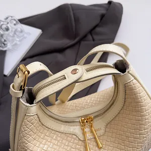 Detailed top view of off-white woven dumpling bag with golden zippers and interior lining