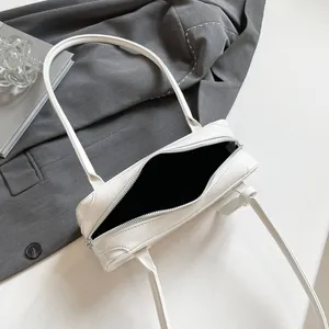 Macro view of white patent leather shoulder bag with silver zipper and black lining