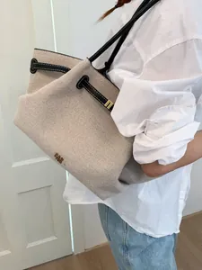 Minimalist beige canvas tote bag with black leather trim for casual office commute