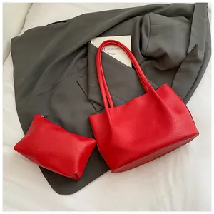 Detail view of large red tote bag set with matching pouch on dark grey blazer background