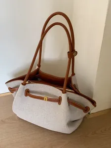 Large gray canvas tote bag with brown leather trim and shoulder straps for daily commute