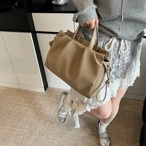 Detailed close-up of beige ruched tote bag showing leather texture and decorative tie knot