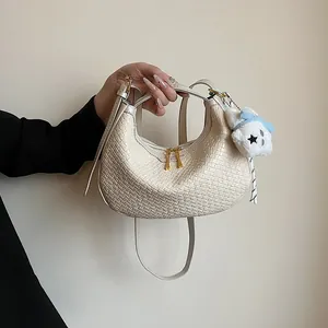 Detail of cream woven crescent bag with gold zippers and plush bear charm