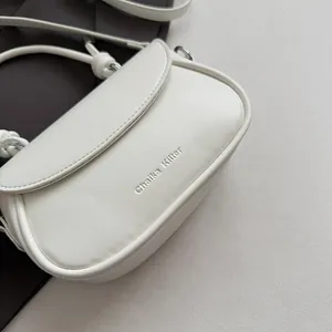 Détail de la texture cuir blanc mat et gaufrage de la marque Chaika Kilter sur le sac
