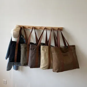 Sacs cabas en toile minimalistes en cinq couleurs suspendus sur des crochets en bois