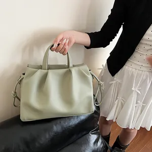 Close-up of sage green ruched cloud bag showing textured lychee pattern and knot detail