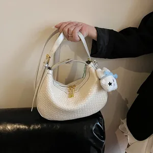 Detail of cream woven hobo bag showing fine texture and cute teddy bear pendant charm