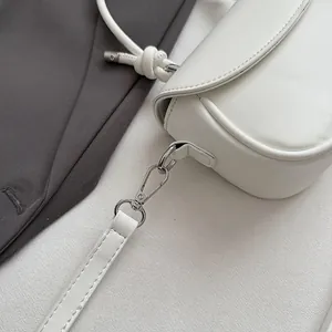 Détail du sac bandoulière en cuir blanc avec fermoir mousqueton argenté et bandoulière nouée