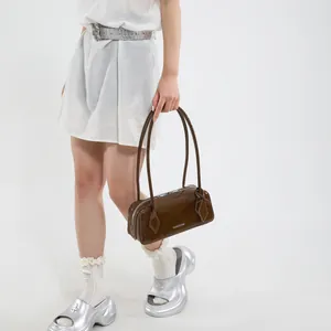Detail of dark brown glossy patent leather shoulder bag with metallic brand plate