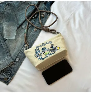 Detail of beige nylon crossbody bag with cute cat embroidery and brown rope strap