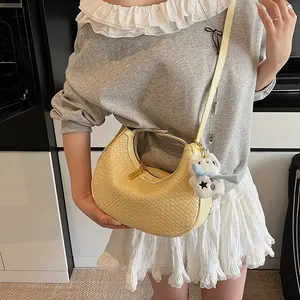 Detail of light yellow woven hobo bag with gold zipper and plush animal charm accessory