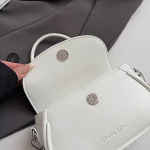 Détail de la boucle magnétique et du logo embossé sur le sac à main en cuir blanc