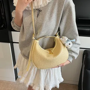Detail of light yellow woven hobo bag with adjustable strap and cute plush charm