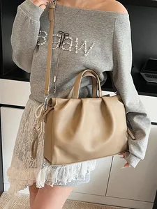 Fashionable beige ruched cloud handbag with shoulder strap shown in a lifestyle setting