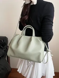 Chic mint green pleated cloud bag in lychee leather shown on a model from the back