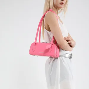 Detail of bright pink leather shoulder bag featuring silver metal bottom studs and glossy finish