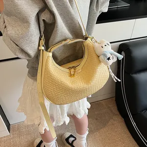 Detail of light yellow woven texture crescent bag with gold zipper and plush charm