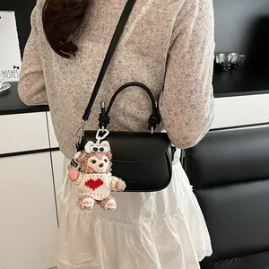 Détail d'un sac noir en similicuir avec poignée torsadée et breloque ours en peluche mignonne