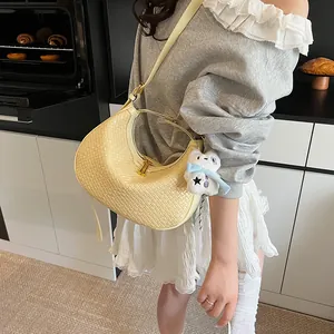 Detail of woven crescent bag in pale yellow with a white plush charm and gold zipper
