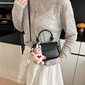 Détail d'un sac à main semi-circulaire en cuir noir avec logo gaufré et boucles en métal