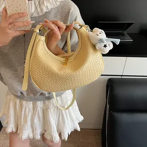 Close-up of light yellow woven hobo bag showing checkered texture and plush charm