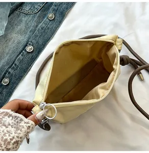 Detail view showing cream nylon bag interior, sturdy rope strap and white ring zipper pull
