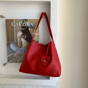 Detailed view of red hobo tote bag featuring pebbled leather texture and silver buckle