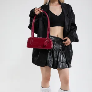 Macro detail of wine red patent leather handbag with glossy finish and silver text logo