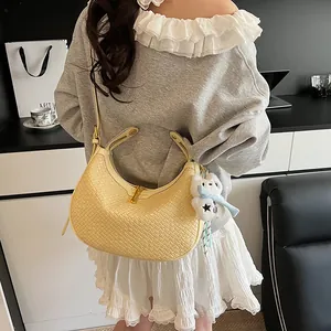 Detail of light yellow woven texture handbag with golden zipper and plush charm