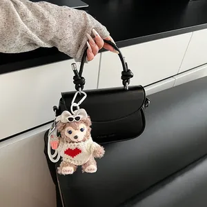Détail du sac à main noir semi-circulaire avec poignée tressée et charm d'ours en peluche