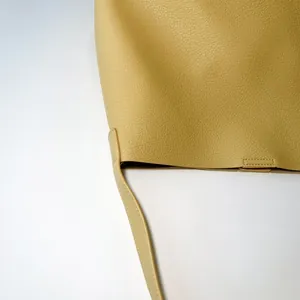Detailed close-up showing the yellow litchi texture leather and strap stitching of the tote