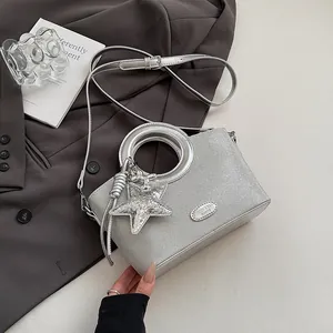 Vue détaillée du sac seau argenté avec grande poignée en métal et breloque étoile sur veste