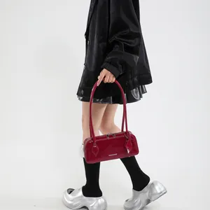 Close-up of glossy burgundy patent leather handbag with silver zipper and slim handles