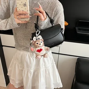 Détail du sac à bandoulière en cuir PU noir avec poignée nouée et pendentif ours