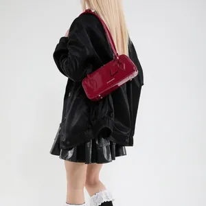 Detail of a burgundy patent leather baguette bag featuring white lettering on the side