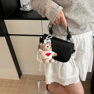 Détail d'un sac demi-lune noir avec poignée nouée élégante et pendentif ours en peluche