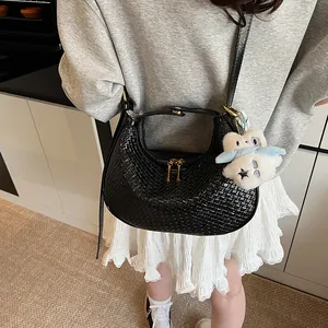Detail of black woven texture hobo bag with gold zipper and plush charm on model