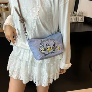 Detail of light blue crossbody bag with cat embroidery and knotted rope strap