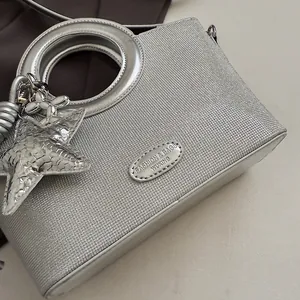 Détail du sac seau argenté scintillant avec poignées métalliques rondes et pendentif étoile